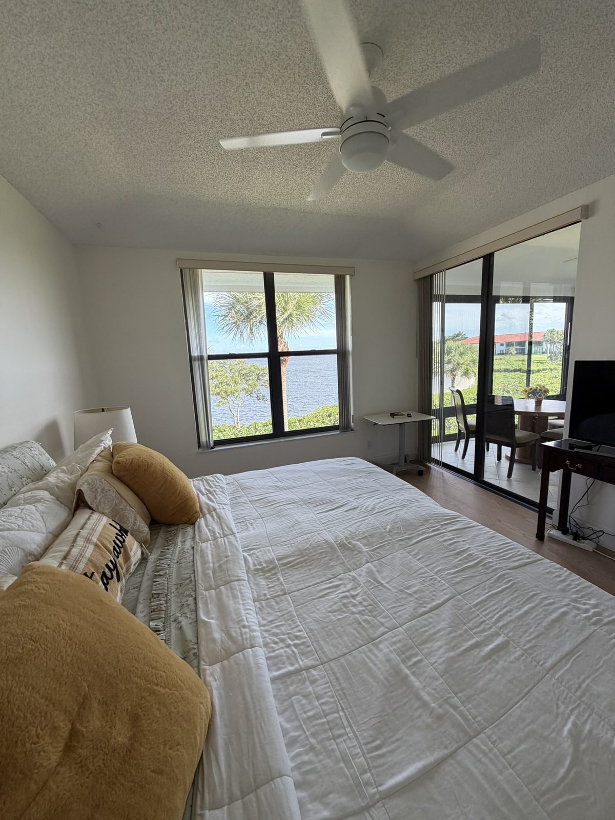 Master bedroom with water view from the bed, ceiling fan, and sliding doors to the screened porch