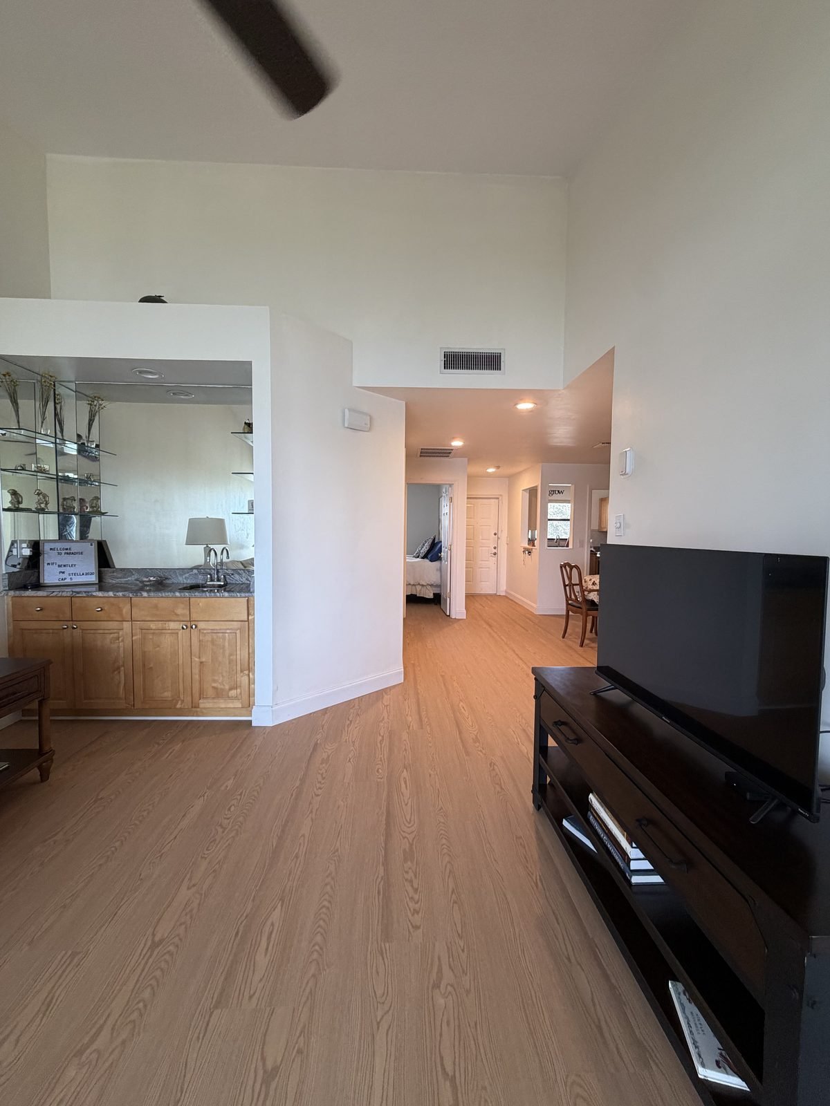 Open living space with wet bar, mirrored glass shelves, and vaulted ceilings